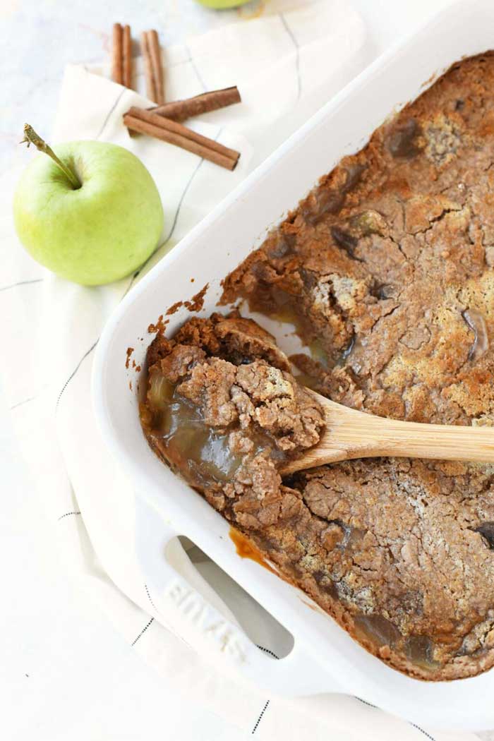 A grene apple near apple spice cake in a white pan.