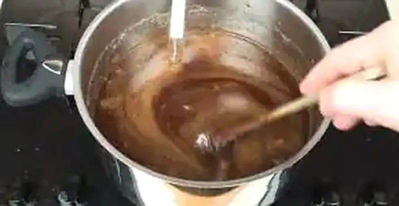 Step 9: Stirring whole dried spices and crushed red peppers into hot apple jelly with thermometer